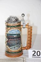 Front and side view of the Comiskey Park baseball stein showing detailed stadium artwork and the baseball-themed pewter lid.