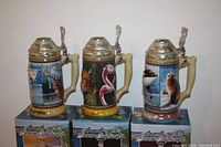 Three Anheuser-Busch ceramic stein mugs from the Animals of the Seven Continents series including North America, South America, and Antarctica, each atop its original box.
