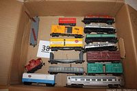 All rolling stock in lot shown in cardboard box from top view. 12 cars including tankers, box cars, poultry cars, gondola, caboose, and passenger car.