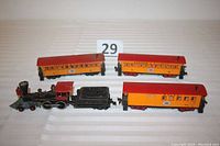 View of all four train pieces in the lot including locomotive, tender, and three passenger cars showing their colors and markings.