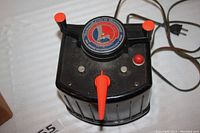 Top view of Lionel transformer showing round logo, voltage dial, direction buttons, and whistle button with attached power cord.