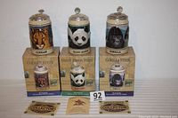 Three steins placed on their original boxes with certificates shown, depicting a Cougar, Giant Panda, and Gorilla from Budweiser's Endangered Species Series.