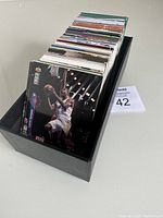 Photo of a large number of sports cards in a black box, showing a basketball player on the front card.