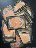 Back sides of Magic: The Gathering cards showing the classic Magic card back design with orange-brown background and blue logo.