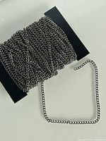 Metal chain wound around a black card, showing link style and thickness.