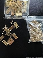 Photo showing mini copper-tone hinges scattered with screws, highlighting hinge size and screws included.