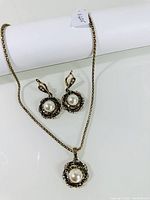 Necklace and earrings set displayed on white stand showing pearl and silver details
