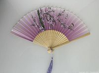 Open folding silk fan showing purple background and cherry blossom with butterflies design.