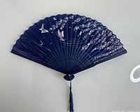 Photo of the blue silk folding fan unfolded showing the bird and blossom design on the fabric.