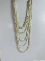 Full view of the five-layer white pearl necklace showing the graduated sizes of pearls across strings.