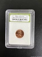 Photo showing the 1958-D Lincoln cent encased in a plastic holder with an International Numismatic Bureau label indicating Brilliant Uncirculated grade.