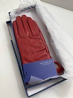 Red women's leather gloves in original box wrapped in white tissue paper, showing brand tag NOVOBJECT.
