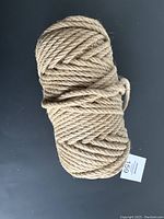 Photo showing the full coiled bundle of the natural fiber twine rope on a black background with a lot tag visible.