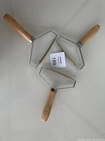 Photo showing three portable lint removers arranged in a triangular layout from front view, highlighting wooden handles and metal blade frames.