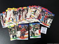 Over 40 hockey rookie sports cards spread out on a black surface, showing player images from various NHL teams including Calgary Flames, Montreal Canadiens, and Hartford Whalers.
