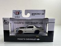 Side view of unopened diecast model car in clear display case with original packaging showing M2 Machines and Chevrolet branding.