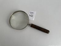 Full view of the vintage magnifying glass showing the round lens and wooden handle.