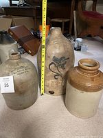 Three jugs side by side on carpet with measuring tape showing height