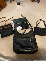 Five bags on beige carpet showing diverse styles: Ralph Lauren small bag, leather shoulder bag, sequin decorative bag, and two travel document holders.