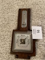 Photo showing the entire wooden wall hanging featuring a metal thermometer and barometer dial with weather terms.