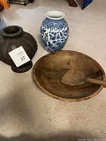 Photo showing all three items: black Mexican vase, blue Dutch ceramic vase, and wooden bowl with ladle together on carpet.
