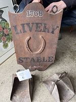 Wooden stable sign with '1768 Livery Stable' printed text and a metal horseshoe attached.