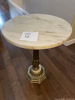 Full view of round white marble top table on wood floor with auction lot number card on top