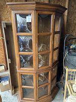 Full view of solid oak display cabinet showing curved glass panes on upper and lower doors and overall cabinet shape.