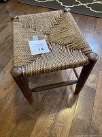 Top view of vintage stool showing twine cord woven seat and wooden legs.
