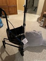 Three-wheeled walker from a slight angled side view showing front compartment and black frame with wheels.