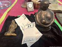 Two bronze Japanese Bundchen style paperweights shown together on black cloth with labels and tags.