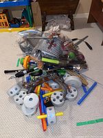 Children's medieval costume accessories on carpet including toy swords, axe, plastic armored vest, and Tinker Toy pieces such as wheels and rods.