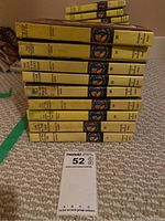 Stack of 9 yellow hardcover Nancy Drew books in worn condition shown from the front with visible spines.