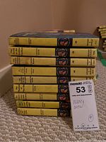 Side view showing the spines of 9 yellowed Nancy Drew books by Carolyn Keene with titles and volume numbers visible under wear.