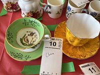 Two teacups and saucers, one green Royal Grafton with bird motif and one yellow Grosvenor with leaf embossing and gold trim.