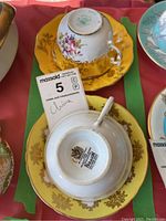 Photo of two china teacups and saucers, one upside down to show the Paragon stamp on the bottom of the saucer and the other showing the design details and floral patterns inside the teacup and the saucer.