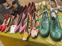 Various pairs of women's shoes laid out on a yellow tablecloth, showing different styles, colors, and materials.