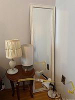 Small round side table with lamps and standing mirror arranged near wall.