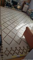 Full view of cream rug in living room with brown diamond pattern