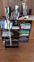 Front view of wooden 3-shelf bookcase filled with hardcover books and wooden magazine rack on top shelf