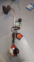 Full view of the Echo GT-225 gas powered trimmer laying on concrete floor with replacement nylon line spools included.