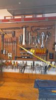 Wide shot of pegboard with various hand tools including hammers, wrenches, levels, screwdrivers and pliers.