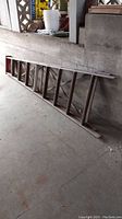10 foot metal extension ladder laid out on a concrete floor, shows length and metal construction.