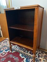 Front left angled view of the Mid Century Modern small shelf showing rectangular shape, two shelves and turned legs.