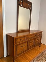Full view of the dresser with attached mirror showing wood finish, drawer arrangement, and overall condition.