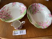 Three bone china items from Royal Albert Blossom Time pattern: one small creamer jug and two oval serving bowls with pink blossom tree and green landscape designs on white background, scalloped edges.
