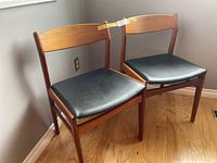 Two teak dining chairs viewed from front corner angle