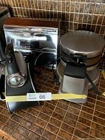 Photo showing the Sunbeam mixer on stand; black body with metal mixing bowl, missing whisks, and the dispenser unit for foil, paper towels, and waxed paper in stainless steel finish.