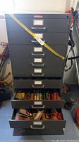 Full view of the 10 drawer metal tool sorter with drawers partially open showing contents including hand tools and plumbing parts.