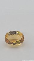Close-up image of a single oval cut deep golden citrine gemstone showing facets and color